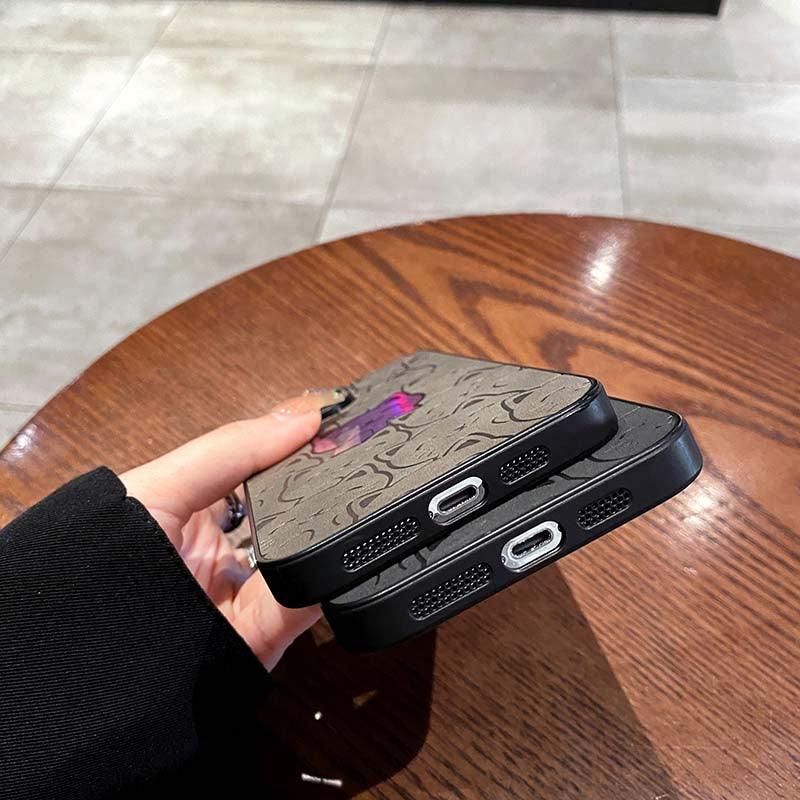 Coque iPhone 14 Pro Max noir en cuir avec motif chat coloré et détails roses sur table en bois. - Wiqeo