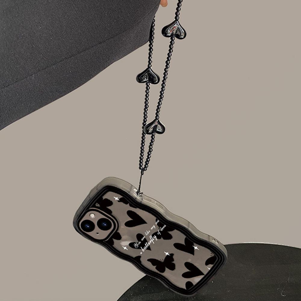 Coque iPhone 12 Pro Max noire avec imprimé papillons et cœurs, équipée d'une sangle noire à motifs cœurs. - Wiqeo